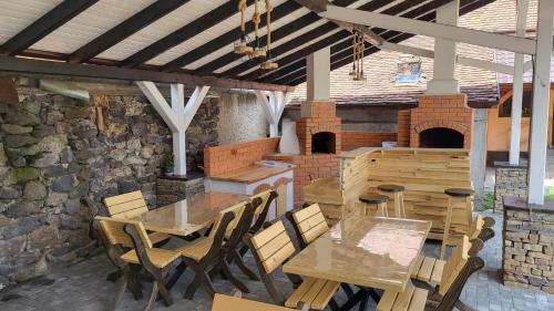 a patio with wooden tables and chairs and a brick wall at PENSIUNEA CASTELANA in Racoşu de Jos