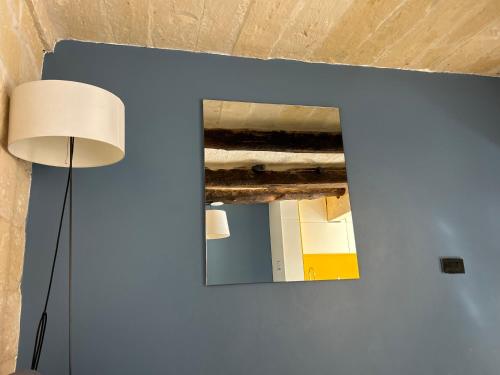 un miroir sur un mur à côté d'une lampe dans l'établissement luxery birgu apartment, à Il-Birgu