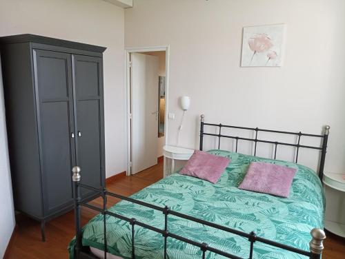 Schlafzimmer mit einem Bett mit grüner Bettwäsche und rosa Kissen in der Unterkunft GITE LA NOTARIALE 