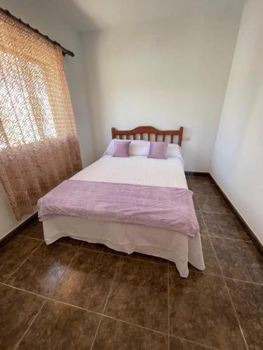 sypialnia z łóżkiem z fioletową pościelą i oknem w obiekcie Lo Jardí de Benifallet w mieście Benifallet