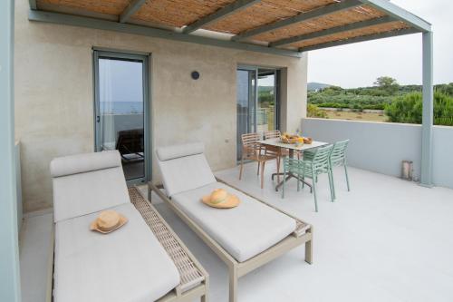 a patio with white chairs and a table with a table at Callisto Seaside Homes & Suites in Marathopolis