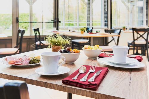 a table with cups and plates of food on it at Hotel Spa Les Saules in Favières