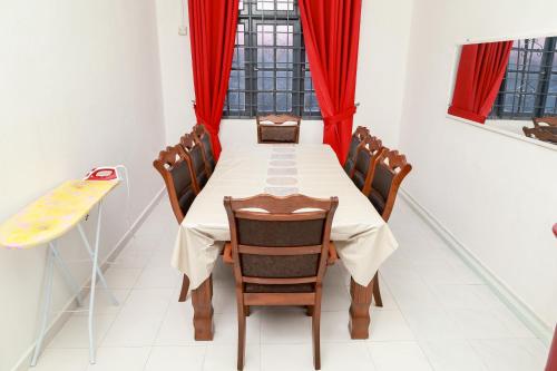 a dining room with a long table and red curtains at D'BALI HOMESTAY - Unifi TV, NETFLIX, Cuckoo, Internet Wifi , Dryer, Washing Machine, Aircond Setiap Bilik & Ruang Tamu in Pasir Puteh