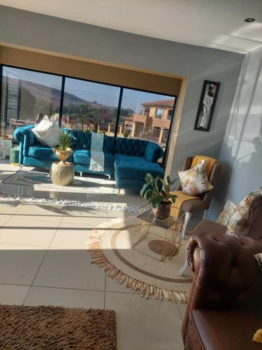 una sala de estar con muebles azules y una gran ventana. en Mohau Accommodation, en Elandsfontein