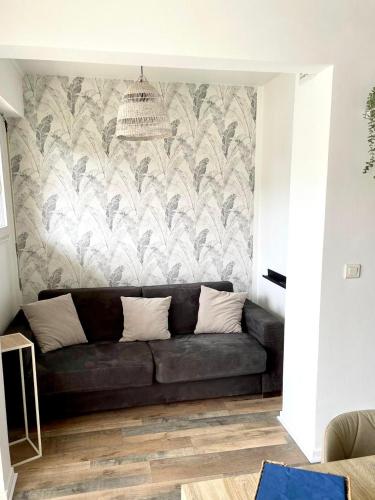 - un canapé noir dans le salon avec un mur dans l'établissement A 10min de Paris La Défense et Roland garros appartement tout confort avec parking et climatisation, à Rueil-Malmaison