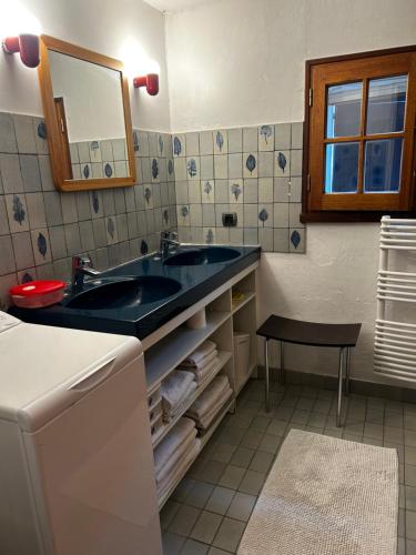 baño con lavabo, espejo y taburete en Capeden maison typique, en Saint-Hilaire-de-Riez