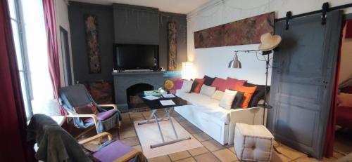 a living room with a white couch and a fireplace at L'Atelier B&B - Esprit bohème, la nature en ville in Carcassonne