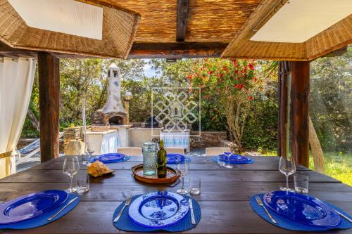 een houten tafel met blauwe borden en wijnglazen bij La Villa Del Paradiso in Stintino