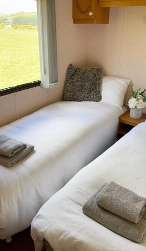two white beds in a room with a window at Mobile Holiday Home in Cushendall