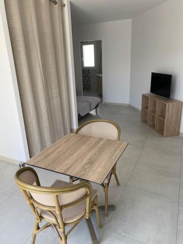 une table et des chaises en bois dans un salon dans l'établissement Studio 2 proche bord de mer 5 mn à pied, à Angoulins-sur-Mer