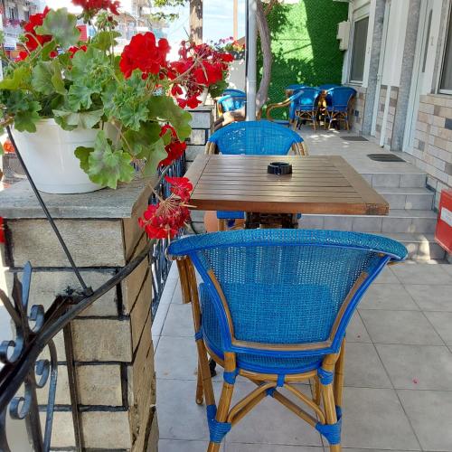 a wooden table with two blue chairs and red flowers at ANNA MARIA Studios in Potos