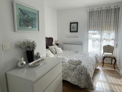 a white bedroom with a bed and a dresser and a chair at Casa Justo in Apiés
