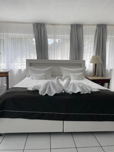 a large bed with black and white sheets and pillows at Hotel Schäfer in Siegen