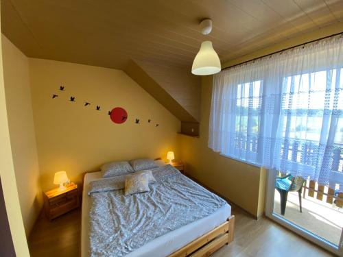 ein Schlafzimmer mit einem Bett und einem Fenster mit Vögeln an der Wand in der Unterkunft Ptasi Raj in Karwia