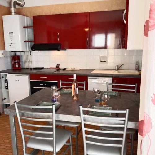 une cuisine avec une table, des chaises et des armoires rouges dans l'établissement Appartement T2 proche plage pour 4 personnes - 4CARIO7, à Canet