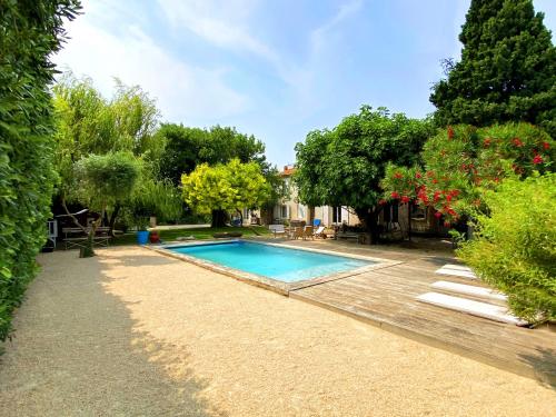 - une piscine dans une cour avec des arbres et une maison dans l'établissement Grande maison, 5 chambres, piscine à 5 min d'Arles, à Fourques