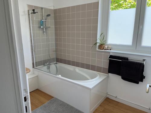 a white bath tub in a bathroom with a window at Charmante Maison - Idéalement Située in Ronchin