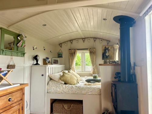 Willowbank shepherds hut في تونتون: غرفة نوم بسرير في زاوية الغرفة