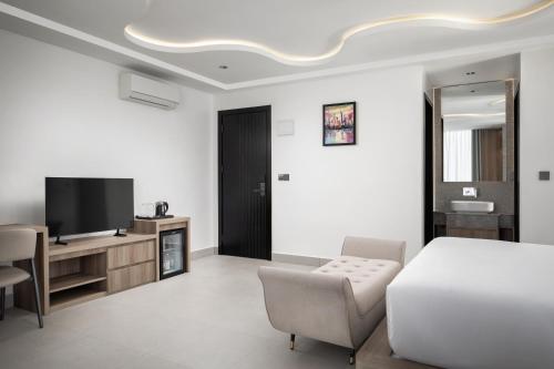 a bedroom with a bed and a tv and a chair at Chaiya Palace Hotel in Phnom Penh