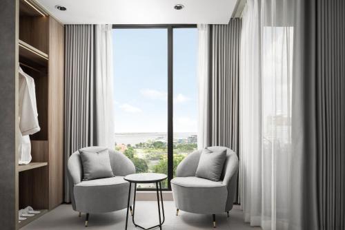 two chairs and a table in a room with a window at Chaiya Palace Hotel in Phnom Penh