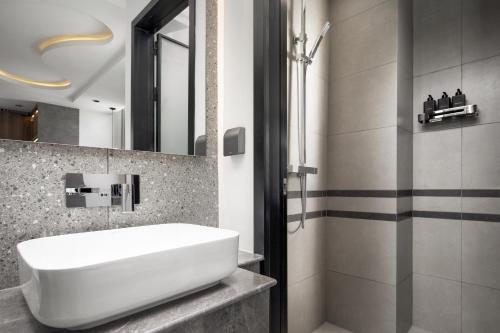 a bathroom with a white sink and a shower at Chaiya Palace Hotel in Phnom Penh