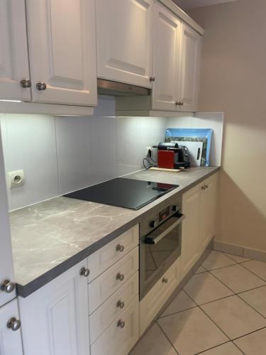 a kitchen with white cabinets and a counter top at Appartement JEAN BART , avec parking privé, meublé tourisme classé 3 étoiles in Mandelieu-la-Napoule