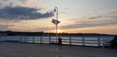 a person sitting on a bench on a pier with a flag at TENNiS Sopot in Sopot