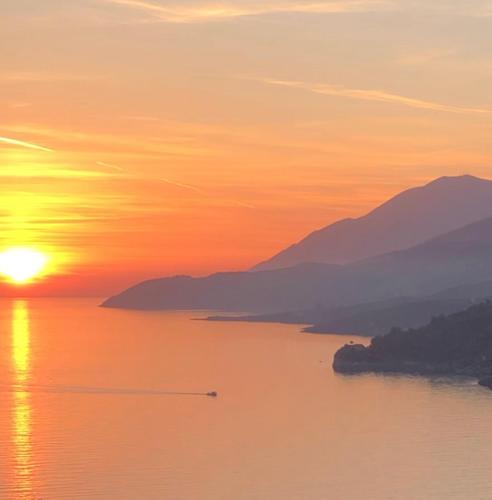 a sunset over a body of water with mountains at Anassa Suites in Himare