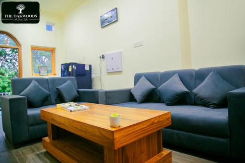 a living room with a blue couch and a wooden table at The Oakwoods in Bhowāli