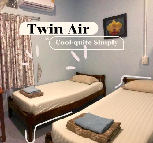 a room with two twin beds and a sign that reads twin air cool quite simply at Vitoonguesthouse2fanrooms & Aircondition in Sukhothai