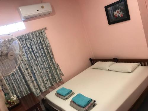 a small bedroom with a bed and a fan at Vitoonguesthouse2fanrooms & Aircondition in Sukhothai