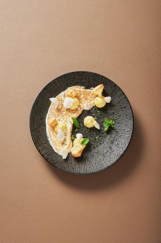 a black plate with food on a table at Hotel Spa Les Saules in Favières