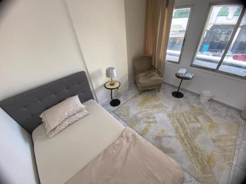 a bedroom with a bed and a chair and windows at Dinar stay in Abu Dhabi
