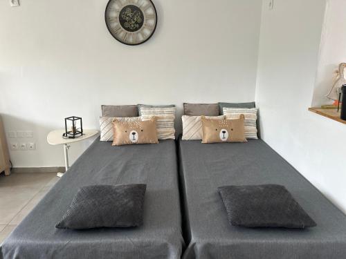 a bed with two pillows and a clock on the wall at La belle étoile in Roye