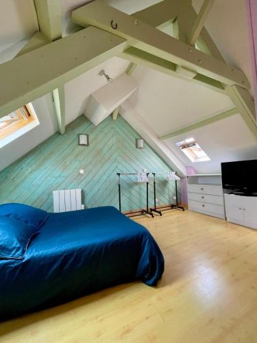 - une chambre mansardée avec un lit bleu dans l'établissement Maison de vacances 5 voyageurs, à Cherbourg en Cotentin