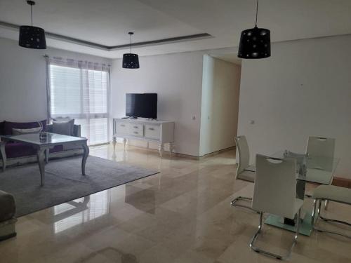 サレにあるSuperbe appartement Marina Rabatのリビングルーム(テレビ、テーブル、椅子付)