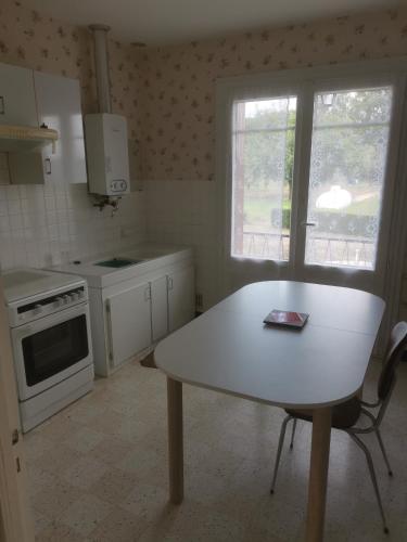 une cuisine avec une table blanche et une fenêtre dans l'établissement le pavillon a la campagne, à La Perche