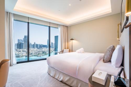 Un dormitorio con una gran cama blanca y una gran ventana. en Elegant 2BR Apartment at The Address Residences Dubai Opera, Downtown Dubai by Deluxe Holiday Homes, en Dubái