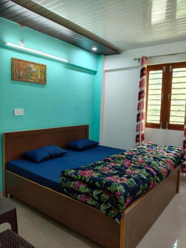 a bedroom with a bed with a blue wall at Him-Kim Homestays in Badrinath