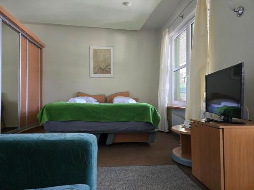 a bedroom with a bed with a green blanket and a tv at Hotel Promenade in Palanga
