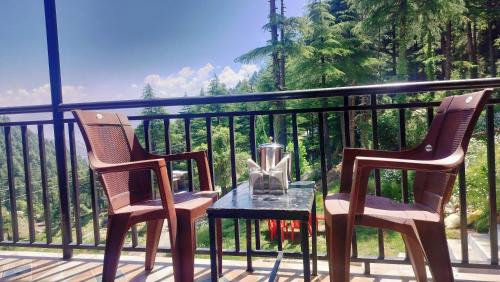 two chairs and a table on a balcony at Kavyansh Forest Valley in Dalhousie