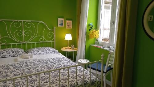 zieloną sypialnię z łóżkiem i oknem w obiekcie B&B Stella Scugnizza w mieście Neapol