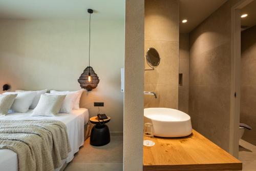a bedroom with a bed and a bathroom with a shower at Aegean Village Beachfront Resort in Amoopi