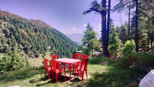 a red table and chairs sitting on a hill with a view at Kavyansh Forest Valley in Dalhousie