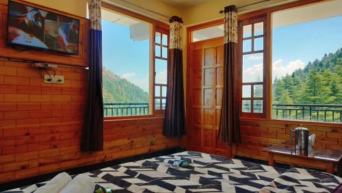 a bedroom with windows with a view of the mountains at Kavyansh Forest Valley in Dalhousie