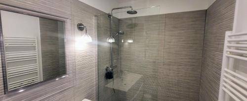 une salle de bain avec une douche avec une porte vitrée dans l'établissement L'angle Panorama 180, à La Grande Motte