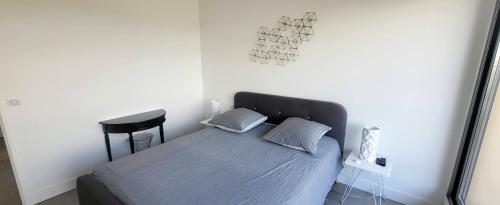 un lit avec deux oreillers et un tabouret dans une chambre dans l'établissement L'angle Panorama 180, à La Grande Motte