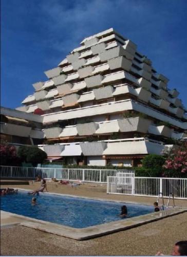 un immeuble avec une piscine devant un immeuble dans l'établissement L'angle Panorama 180, à La Grande Motte