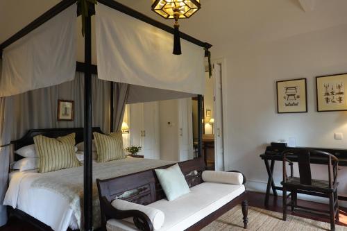 a bedroom with a canopy bed and a chair at Sela Chiangmai in Chiang Mai