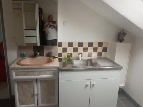 un homme prenant une photo d'une salle de bains avec lavabo dans l'établissement L'esteve, à Coulogne